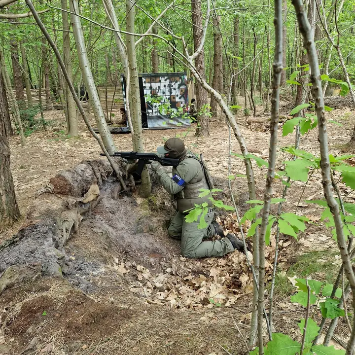 Speler in dekking achter een boomstam in het bos
