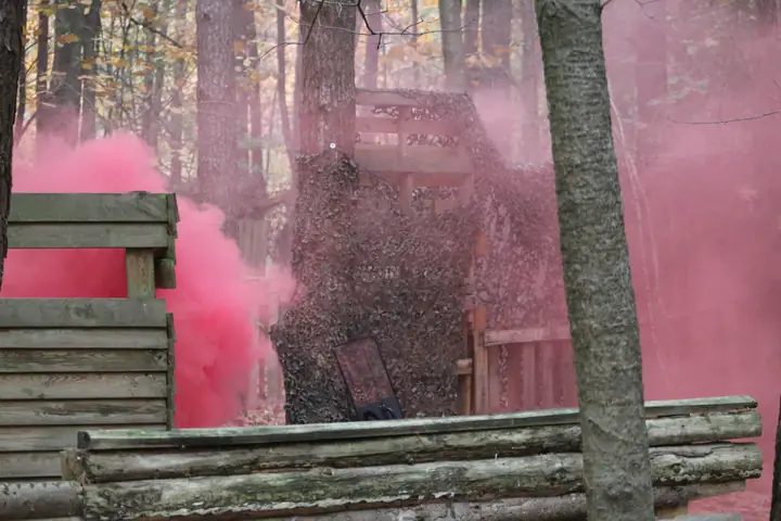 Roze rook van een rookgranaat bij een houten fort